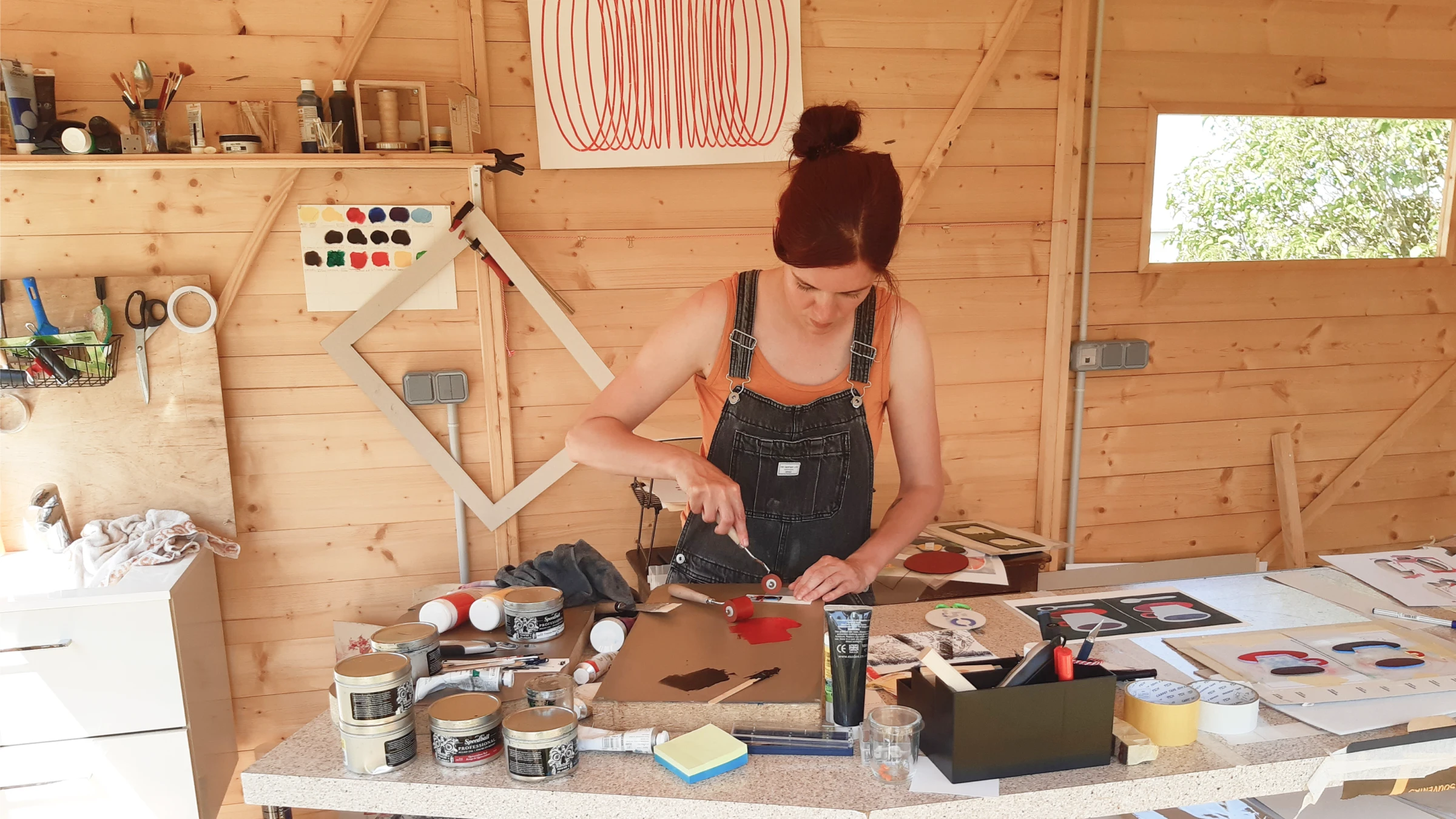 Photographie de l’artiste dans son atelier en train d’imprimer une estampe à la main.